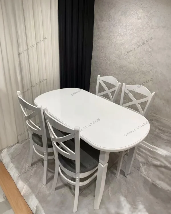 A dining room featuring a wooden table surrounded by four chairs, with soft lighting creating a warm atmosphere